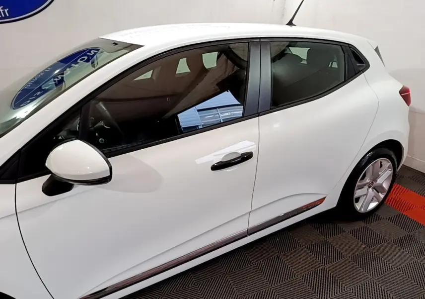 Profil côté gauche d'une Renault Clio Business blanche, mettant en valeur la ligne fluide et les jantes alliage.