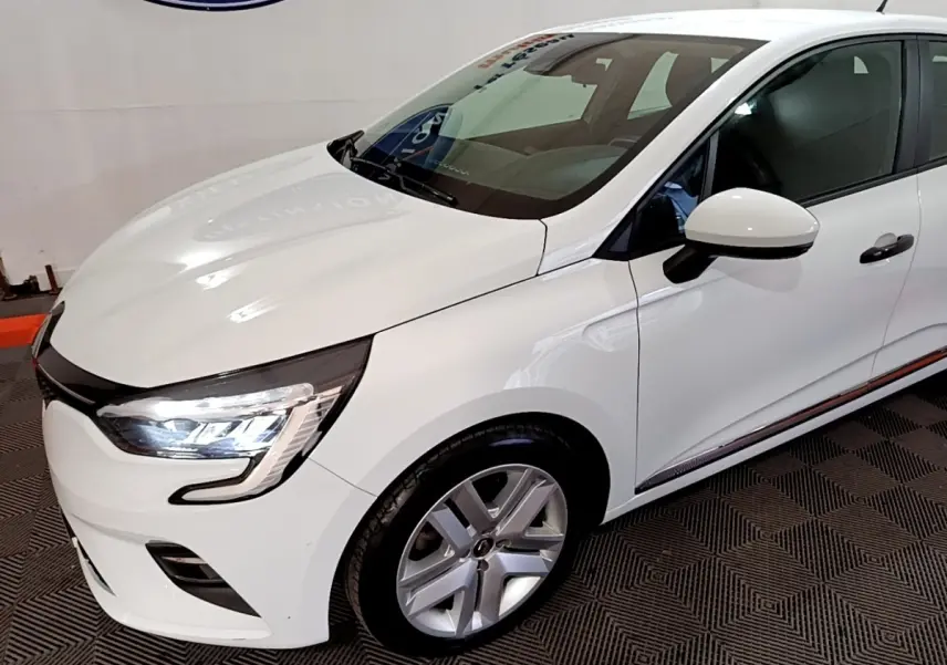 Vue 3/4 avant droit d'une Renault Clio Business blanche avec phares LED allumés et jantes alliage.