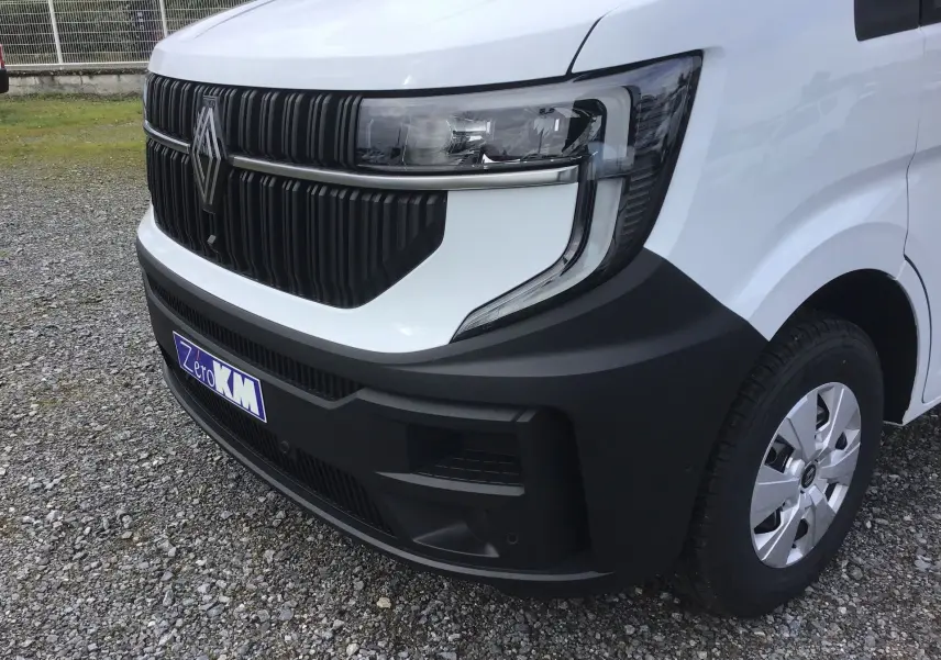 Gros plan sur l’avant droit du Renault Master blanc, mettant en valeur la calandre noire et le phare moderne.