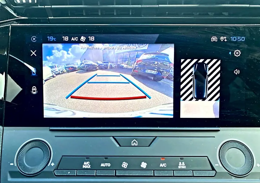 Écran tactile intérieur montrant la caméra de recul active d'une Peugeot 308 gris, avec affichage des aides au stationnement.