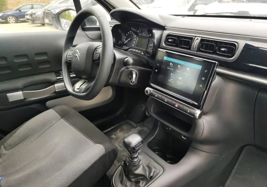Vue intérieure côté conducteur de la Citroën C3 Société blanche, montrant le volant, la console tactile et la boîte manuelle.