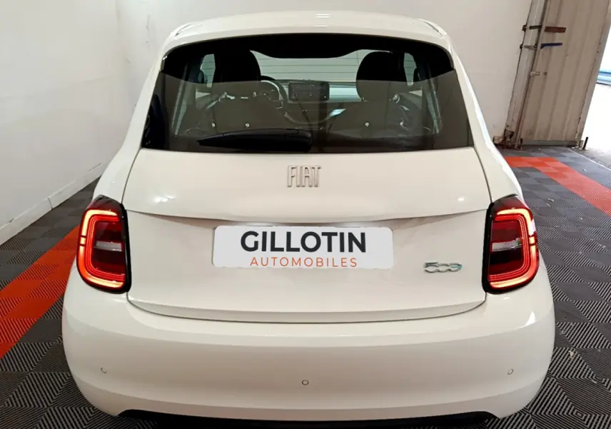 Vue arrière d'une FIAT 500 blanche avec feux LED allumés dans un garage fermé.
