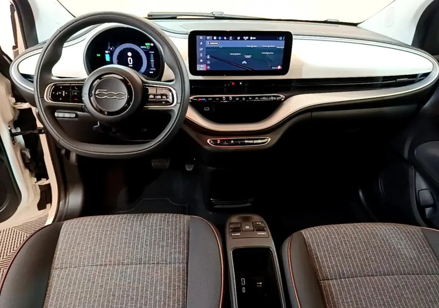 Vue intérieure avant de la FIAT 500 électrique blanche 2022, tableau de bord épuré avec écran tactile central et volant multifonctions.