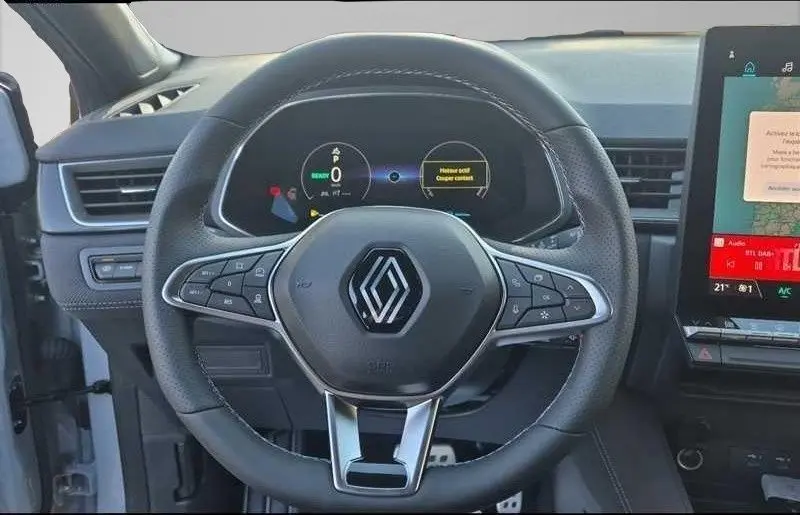 Vue intérieure centrée sur le volant noir du Renault Captur E-Tech hybride 2025 avec tableau de bord numérique et écran tactile.