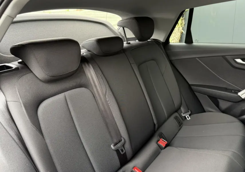 Vue intérieure du siège arrière côté droit de l'Audi Q2 35 TFSI noir Mythe avec appuie-têtes et ceintures visibles.