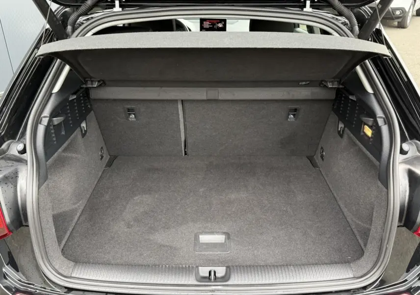 Coffre ouvert vu de l'arrière d'un Audi Q2 noir Mythe, montrant l'espace de chargement et le hayon électrique.