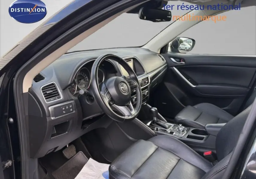 Intérieur noir du Mazda CX-5 2017 vu côté conducteur, avec volant multifonction et console centrale moderne.