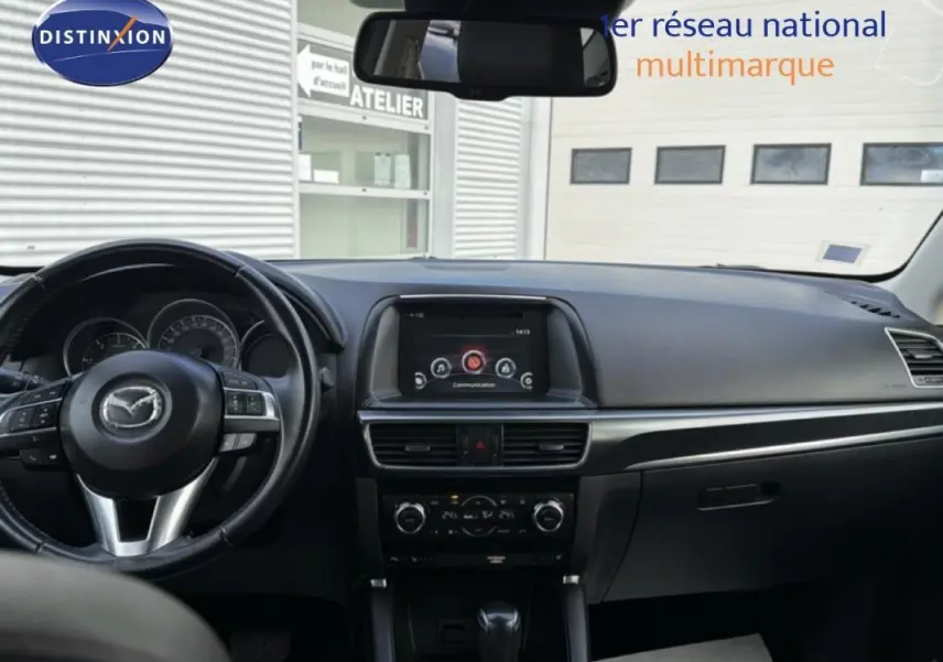 Vue intérieure frontale du tableau de bord noir du Mazda CX-5 2017 avec écran central et volant multifonction.