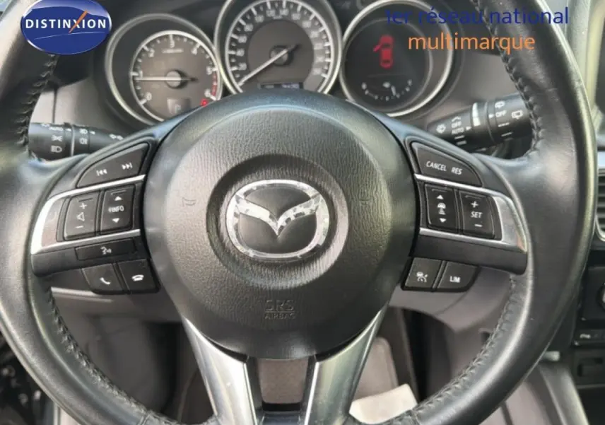 Gros plan sur le volant multifonction noir du Mazda CX-5 2017 avec commandes intégrées et tableau de bord visible.