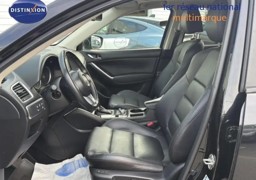 Intérieur noir du Mazda CX-5 2017, vue côté conducteur avec sièges cuir et console centrale visible.