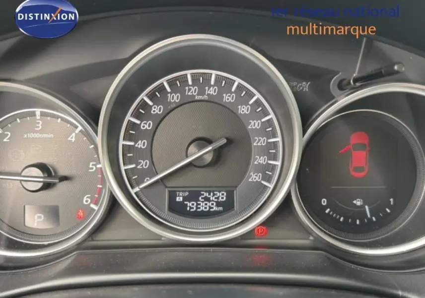 Tableau de bord du Mazda CX-5 noir 2017 montrant compte-tours, vitesse et niveau carburant avec porte ouverte à gauche.