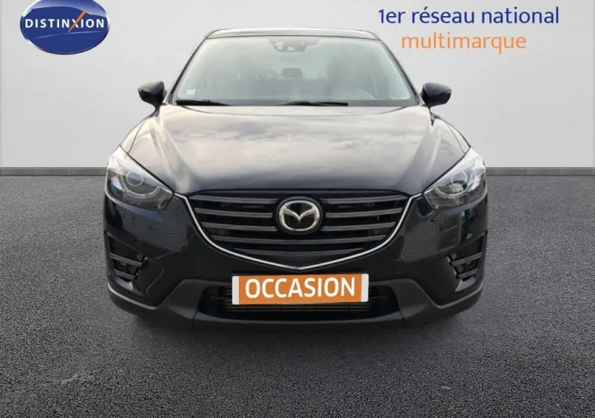 Vue frontale d'un Mazda CX-5 noir 2017 avec calandre chromée et phares LED allumés sur parking.