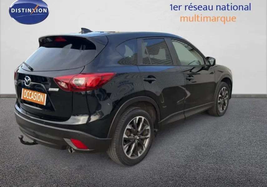 Vue 3/4 arrière droite d'un Mazda CX-5 noir 2017 avec jantes alliage 19 pouces et attelage fixe visible.