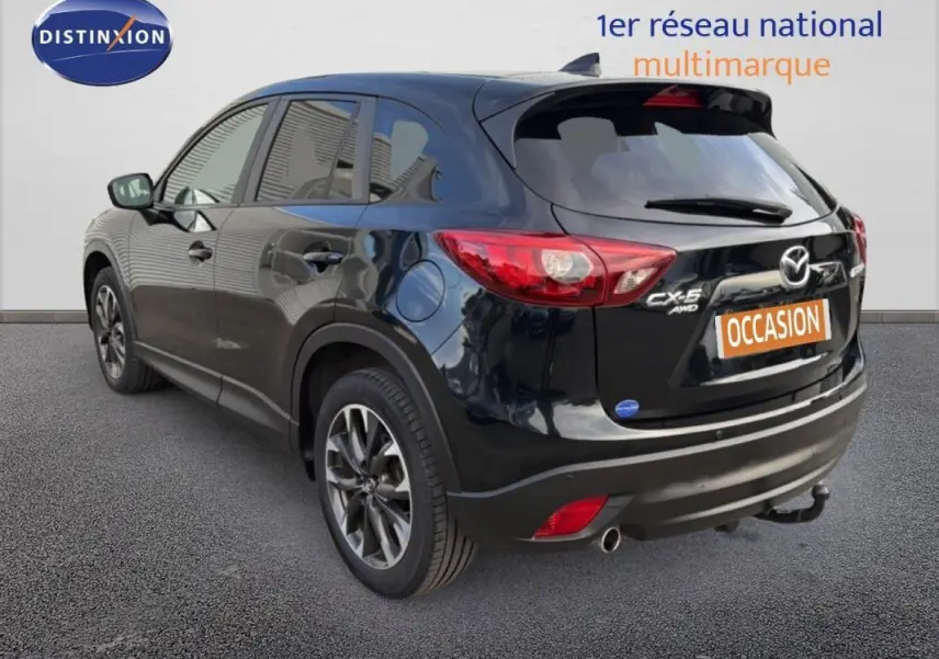 Vue 3/4 arrière droite d'un Mazda CX-5 noir 2017 avec jantes alliage 19 pouces et attelage fixe visible.