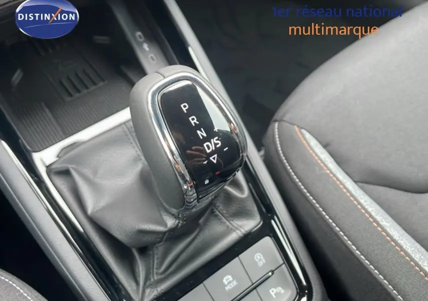 Le levier de vitesse automatique DSG7 de la Skoda Kamiq 2025 en gros plan avec sellerie tissu gris et surpiqûres orange.
