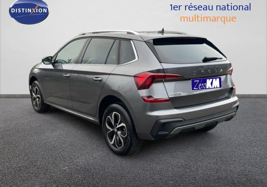 Vue 3/4 arrière droite d'un Skoda Kamiq gris graphite métal 2025 avec jantes alliage bicolores et barres de toit.