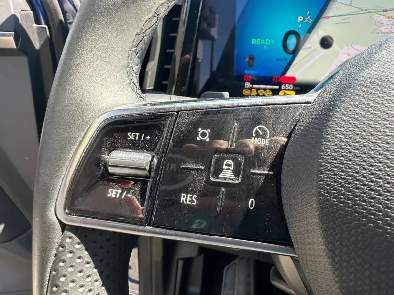 Gros plan sur les commandes multifonctions noires à gauche du volant du Renault Austral 2025, avec écran digital en arrière-plan.