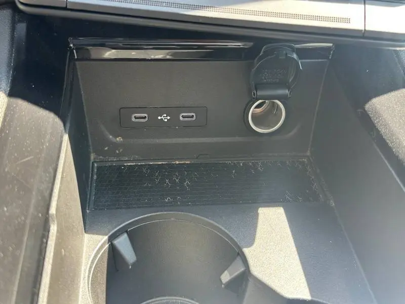 Gros plan intérieur sur la console centrale du Renault Austral bleu, montrant prises USB-C et prise 12V avec porte-couvercle.