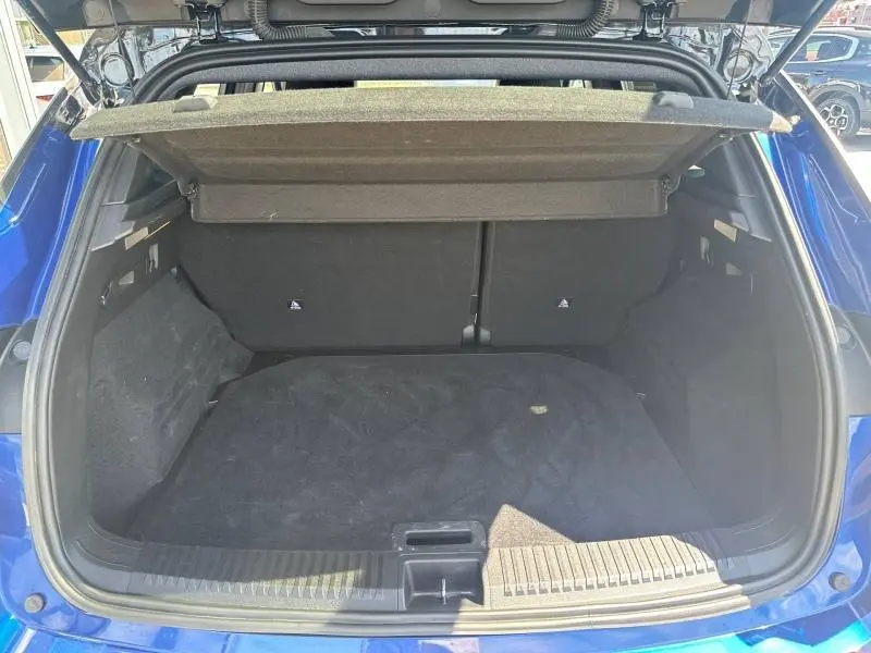 Coffre ouvert vu de l'arrière du Renault Austral bleu Iron avec cache-bagages et intérieur noir.