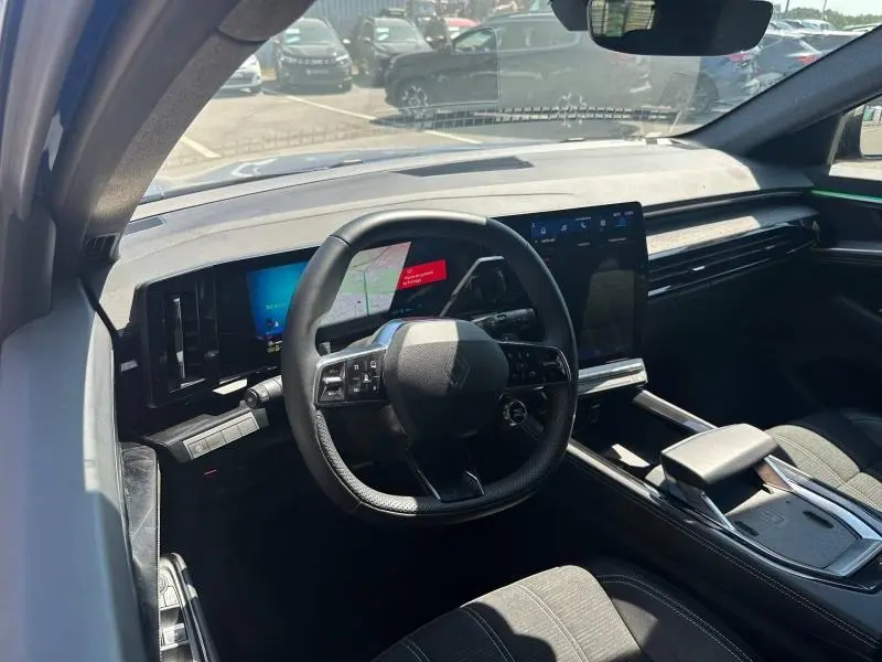 Vue intérieure du poste de conduite du Renault Austral 2025, avec volant multifonction et grand écran tactile central.