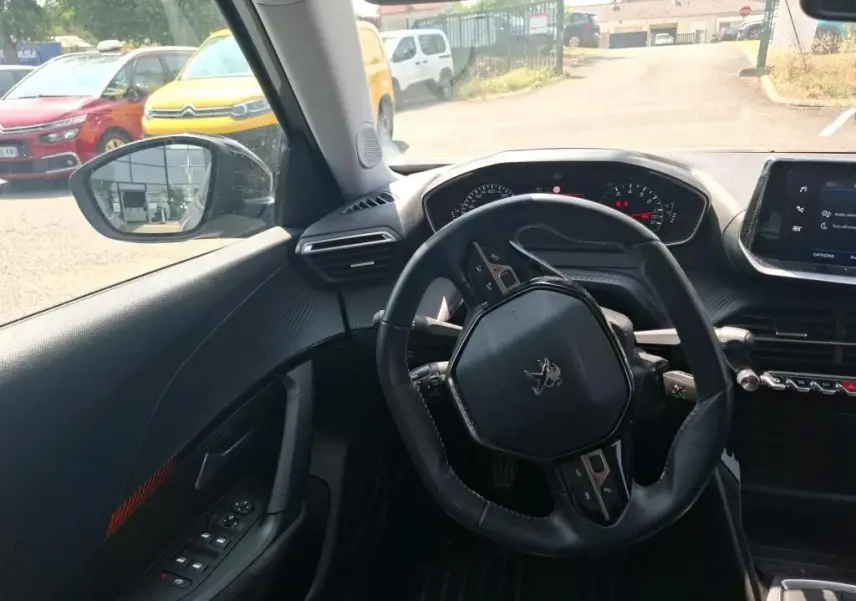 Vue intérieure côté conducteur du Peugeot 2008 gris Artense 2022, sièges tissu noir et tableau de bord moderne.