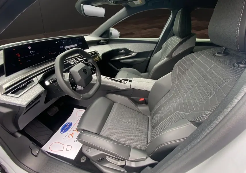Intérieur avant droit du Peugeot 3008 2024, sièges tissu noir et gris, tableau de bord numérique large et moderne.
