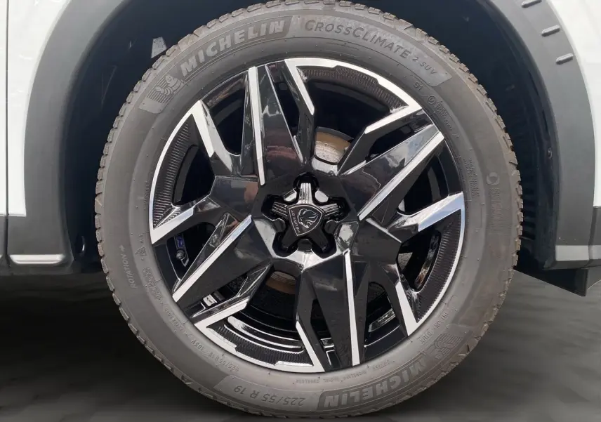 Gros plan sur la roue avant droite du Peugeot 3008 blanc Okenite avec jante alliage noire et argentée design moderne.