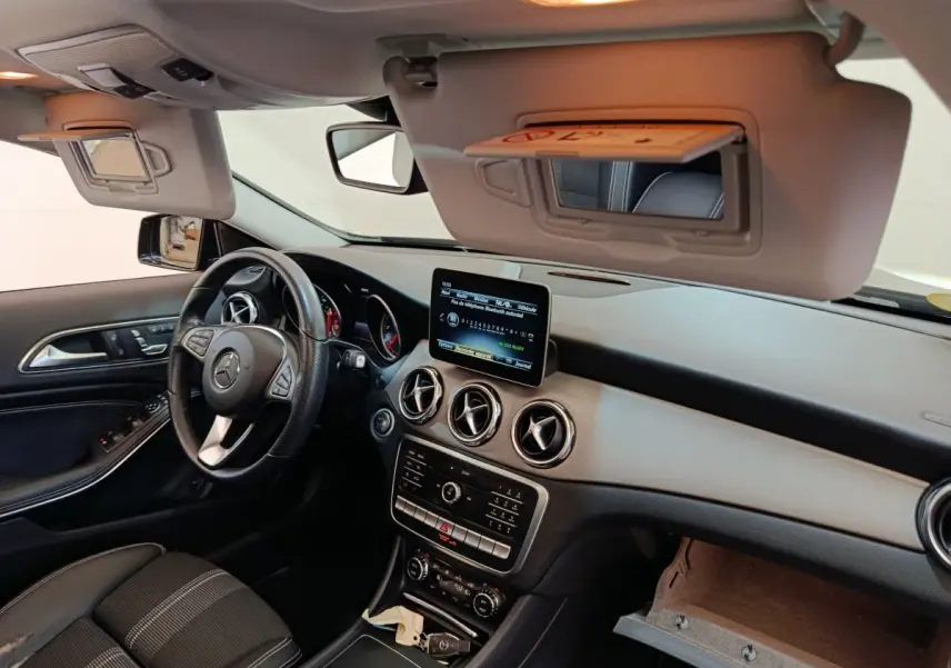Vue intérieure côté conducteur du tableau de bord noir et gris du Mercedes GLA 220 d avec écran central et volant cuir multifonctions.