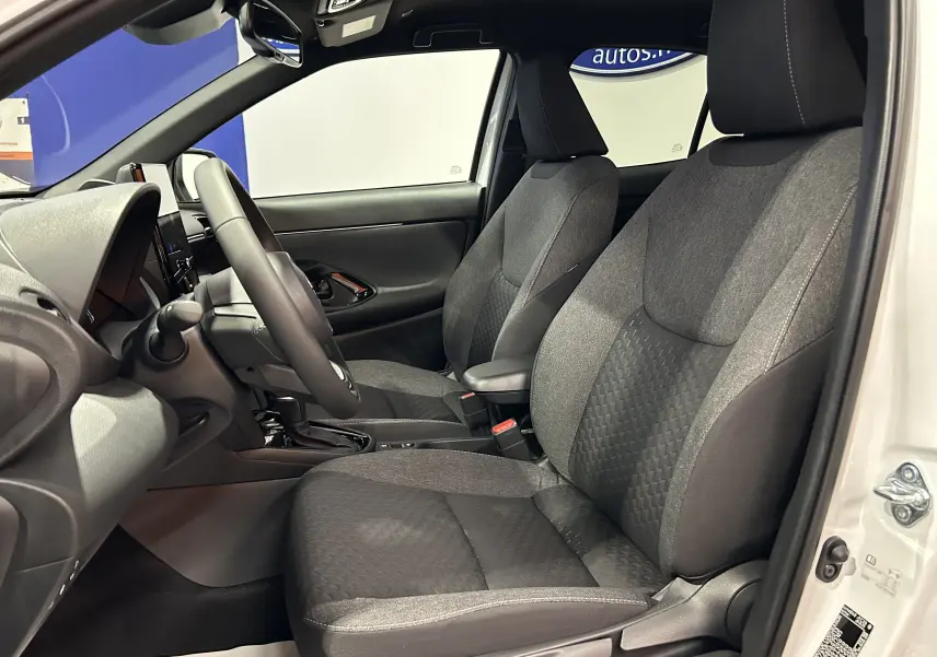 Vue intérieure côté conducteur de la Toyota Yaris Cross 130 Design blanche, sièges tissu gris et console centrale visible.