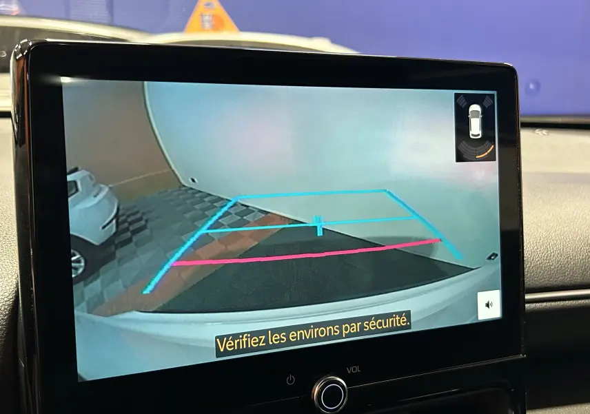 Écran de caméra de recul affichant l'arrière blanc d'une Toyota Yaris Cross 130 Design MY25 en intérieur.