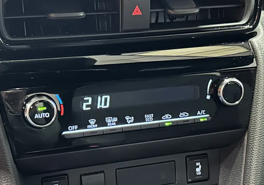 Gros plan sur la commande de climatisation automatique affichant 21°C dans une Toyota Yaris Cross blanche 2025.