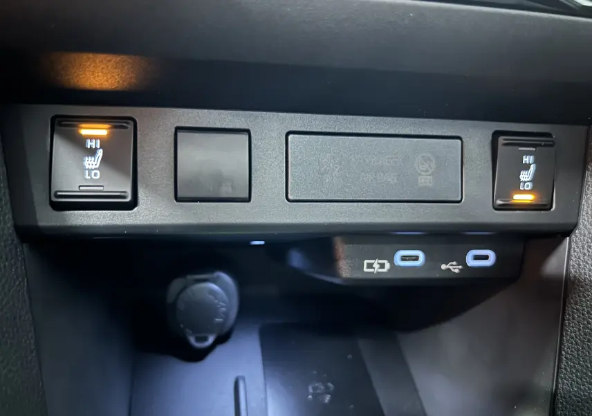 Gros plan sur les commandes des sièges chauffants avant et les ports USB-C du Toyota Yaris Cross blanc 2025.