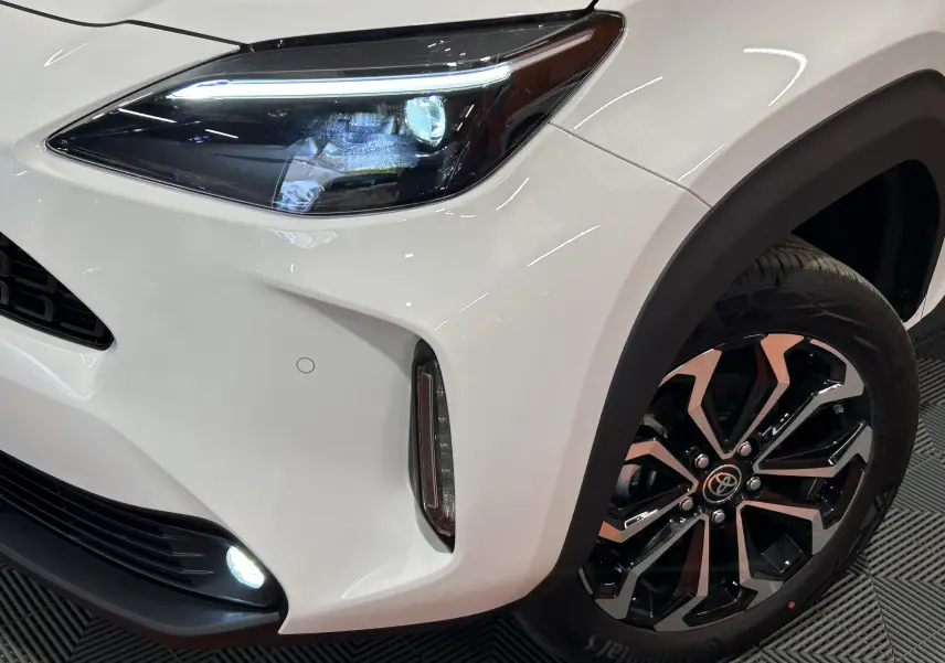 Gros plan sur l'avant droit blanc du Toyota Yaris Cross 130 Design MY25 avec phares LED et jantes alliage noires.
