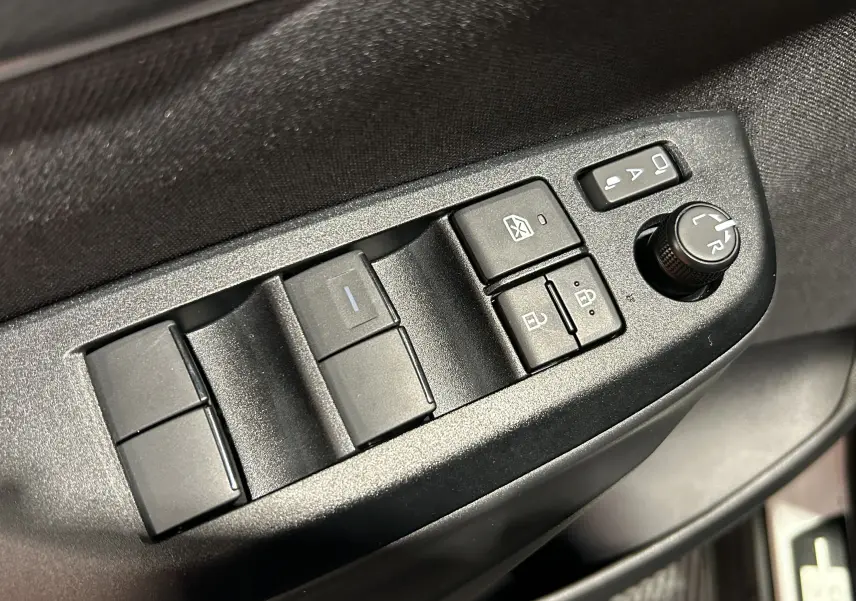 Gros plan sur les commandes des vitres et rétroviseurs côté gauche de la porte d’une Toyota Yaris Cross blanche 2025.