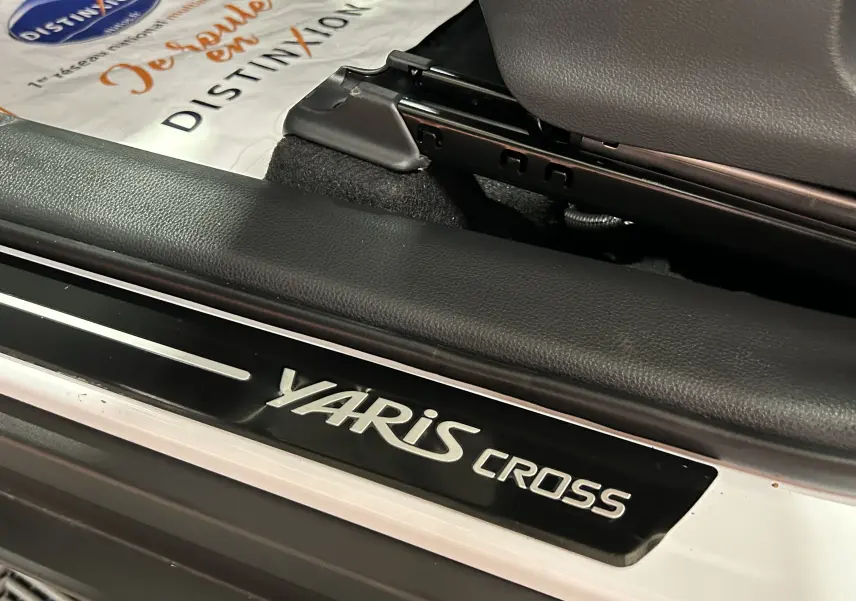 Gros plan sur la plaque de seuil de porte Yaris Cross noire et argentée, intérieur tissu d'un Toyota blanc 2025.