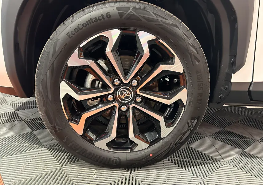 Gros plan sur la roue avant droite de la Toyota Yaris Cross blanche 2025 avec jante alliage noire et argentée.