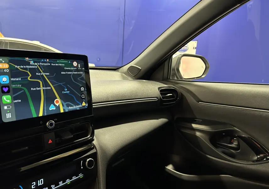 Intérieur de la Toyota Yaris Cross 2025 blanc, vue côté passager avec écran tactile et tableau de bord moderne.