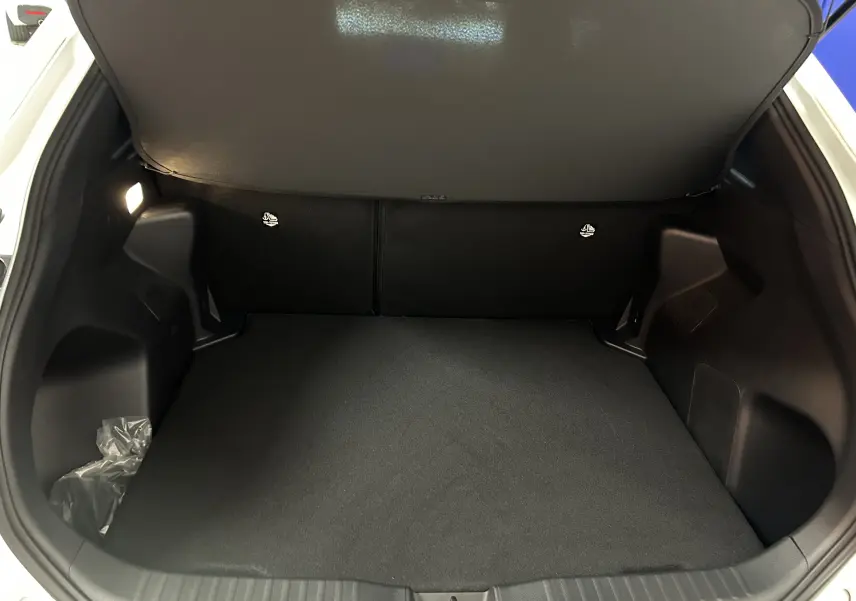 Coffre ouvert d'une Toyota Yaris Cross blanche 2025, vue arrière montrant un espace de chargement propre et spacieux.