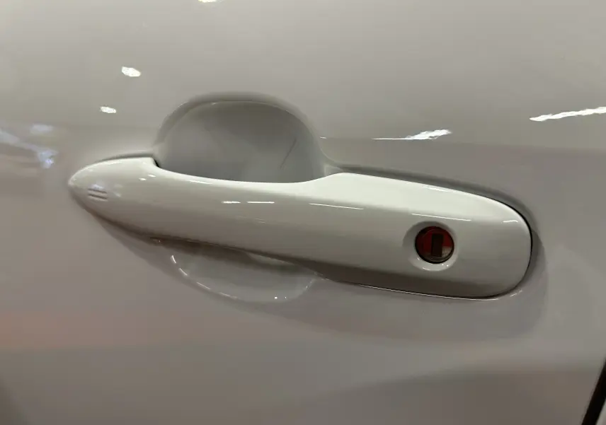 Poignée de porte blanche en gros plan sur le côté gauche d'une Toyota Yaris Cross 130 Design 2025 hybride.