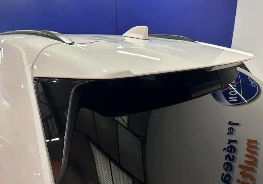 Toit blanc de la Toyota Yaris Cross 130 Design 2025 avec antenne requin et vitre arrière teintée vue de trois quarts arrière côté gauche.