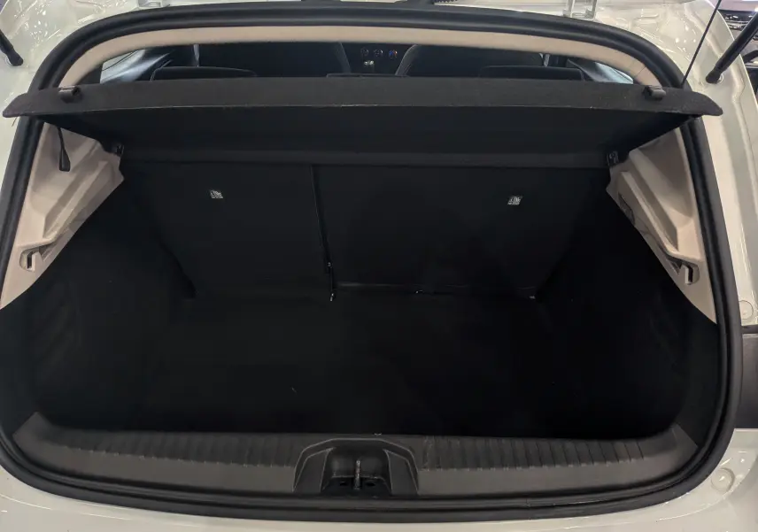 Coffre ouvert vu de l'arrière d'une Renault Clio V Blanc Glacier, montrant l'espace de chargement vide et la plage arrière.