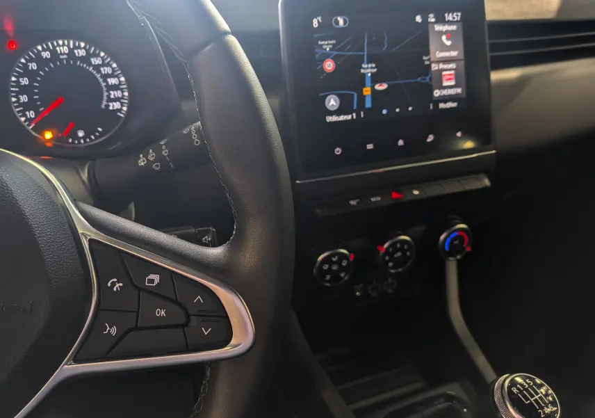 Intérieur de Renault Clio V Blue dCi 100 Business 2021, vue du volant gauche et console centrale avec écran tactile et levier de vitesse manuel.