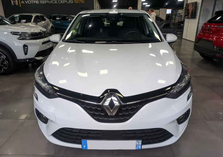 Renault Clio V Blue dCi 100 CH BUSINESS blanc glacier vue de face en intérieur avec calandre noire distinctive.