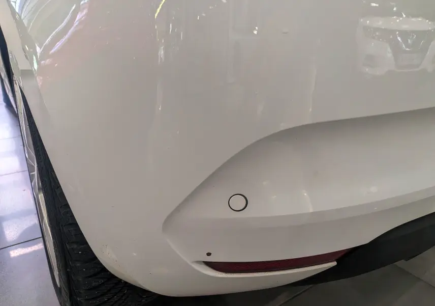 Gros plan sur l'angle arrière gauche blanc glacier d'une Renault Clio V Blue dCi 100 CH BUSINESS avec capteur de recul visible.