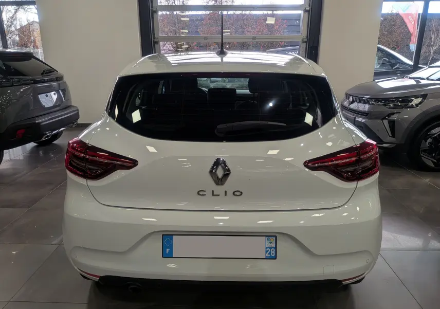 Vue arrière d'une Renault Clio V Blanc Glacier, mettant en valeur ses feux arrière LED et son logo central chromé.