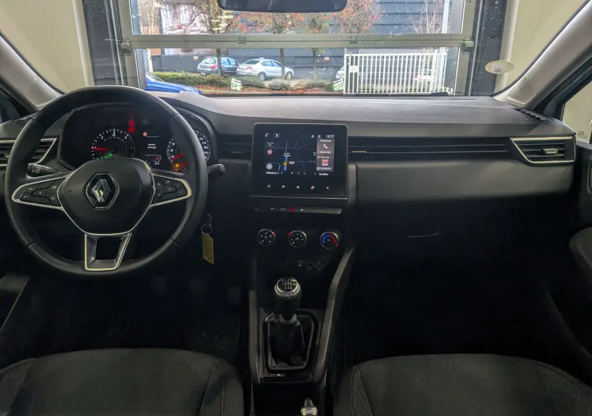 Vue intérieure avant de la Renault Clio V Business 2021, tableau de bord noir avec écran tactile et levier de vitesse manuel.