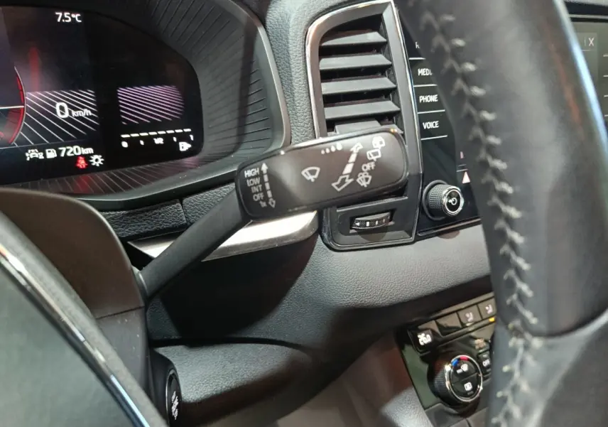 Gros plan sur le combiné d'instruments et la commande d'essuie-glace à gauche du volant cuir dans un Skoda Karoq 2024.