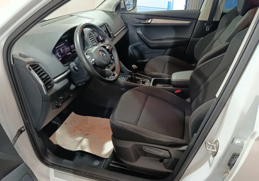 Intérieur avant droit du Skoda Karoq 2024 avec sièges noirs, volant cuir multifonctions et tableau de bord digital.