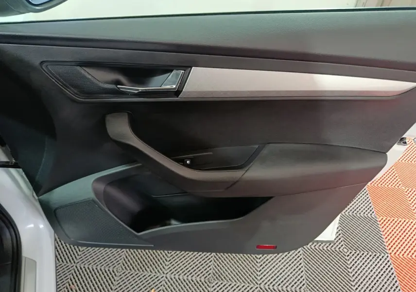 Vue intérieure de la porte côté gauche noire avec poignée argentée et insert décoratif gris du Skoda Karoq 2024.