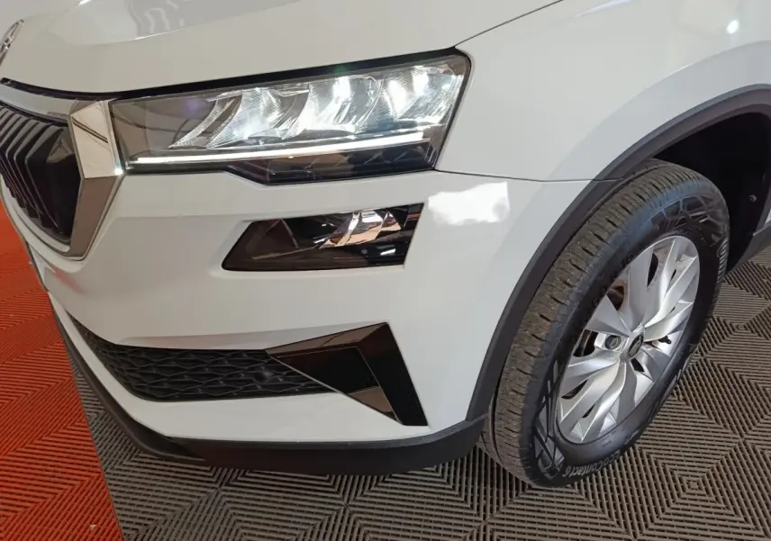 Gros plan sur l'avant droit blanc du Skoda Karoq 2024, mettant en valeur le phare LED et la roue alliage.